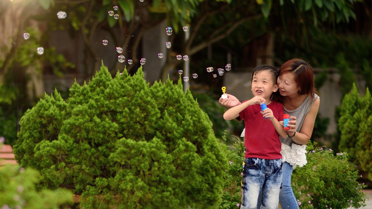 A kid and his mother are playing with bubbles; image used for "build emergency savings" article.