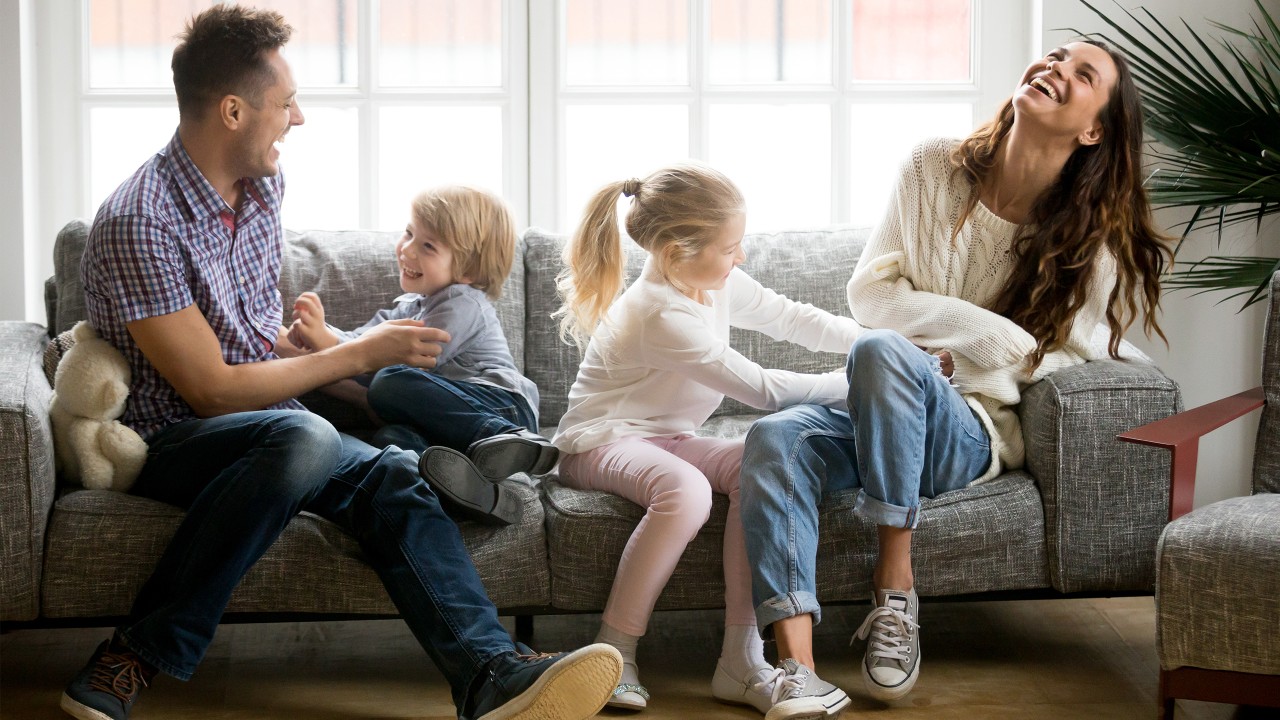 parents happily playing with their son and daughter on the sofa; image used for HSBC Loan page.