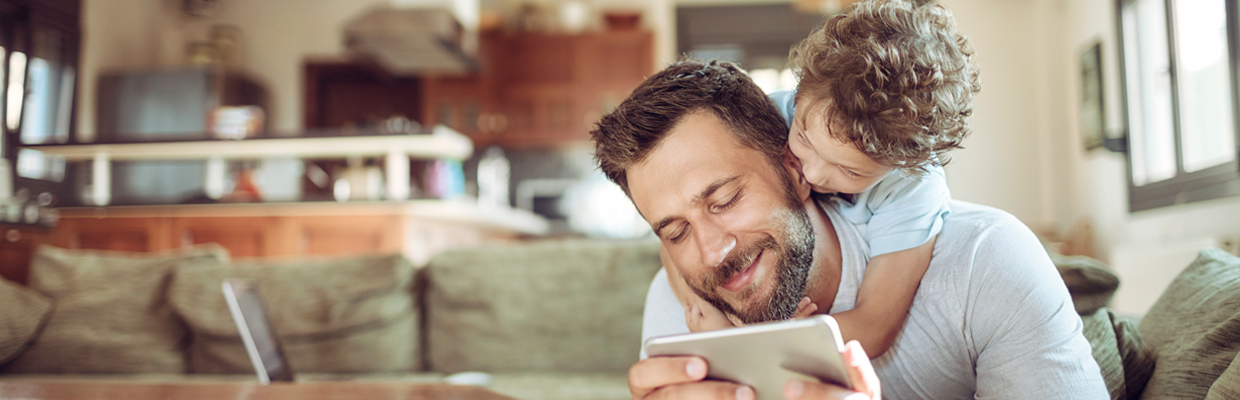 father and son using mobile on a sofa at home; image used for HSBC LK digital banking at home page