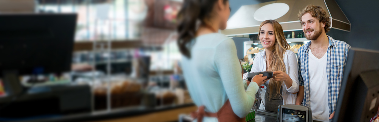 A young couple is paying via a POS device holding by a staff in a coffee shop; image used for HSBC Sri Lanka contactless page.