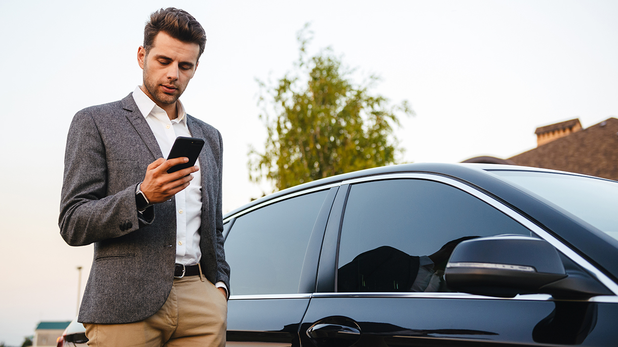 a man checking his mobile phone beside a car; image used for HSBC LK Advance Bank in your pocket page.