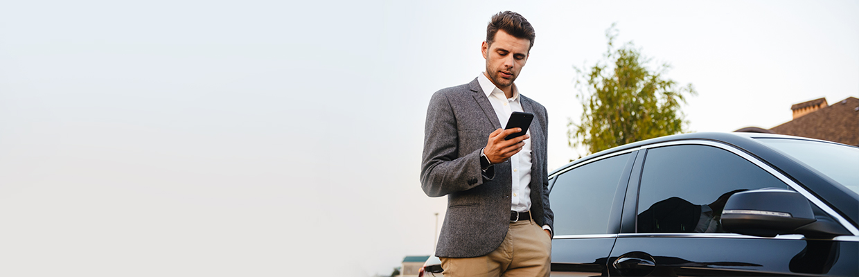 a man checking his mobile phone beside a car; image used for HSBC LK Advance Bank in your pocket page.