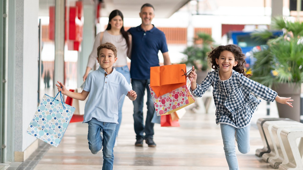 A boy and a girl running happily with shopping bags with their parents walking behind them; image used for HSBC Sri Lanka credit card offer page