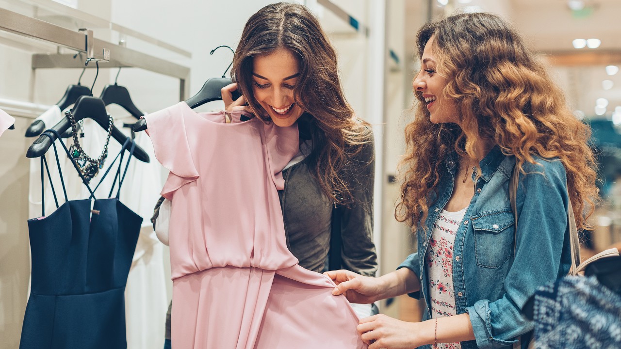 two young women happily picking up dresses; image used for HSBC Sri Lanka credit card shopping offer page.