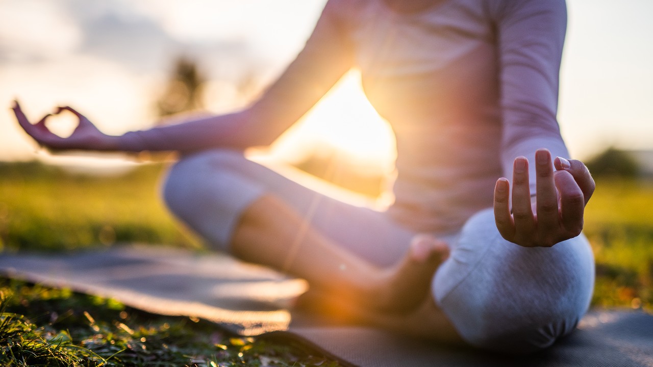 A woman wearing yoga outfit in Sukhasana pose on a lawn; image used for HSBC Sri Lanka credit card  health offer page