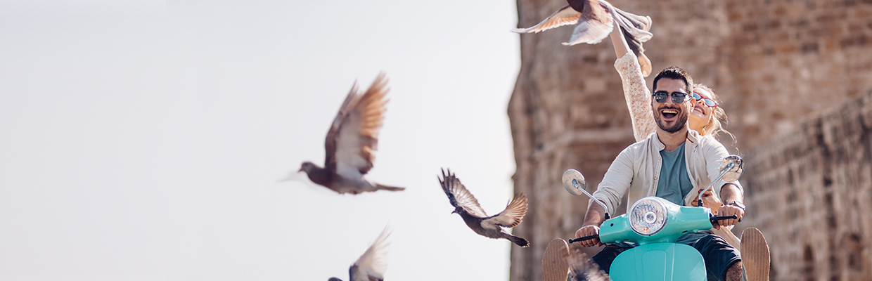 A young couple riding a motor excitedly with several birds taking off;  image used for HSBC Sri Lanka credit card other offer page