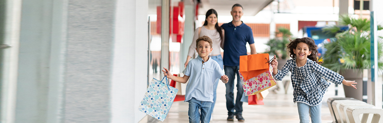 A boy and a girl running happily with shopping bags with their parents walking behind them; image used for HSBC Sri Lanka credit card offer page