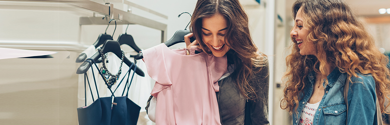 two young women happily picking up dresses; image used for HSBC Sri Lanka credit card shopping offer page.