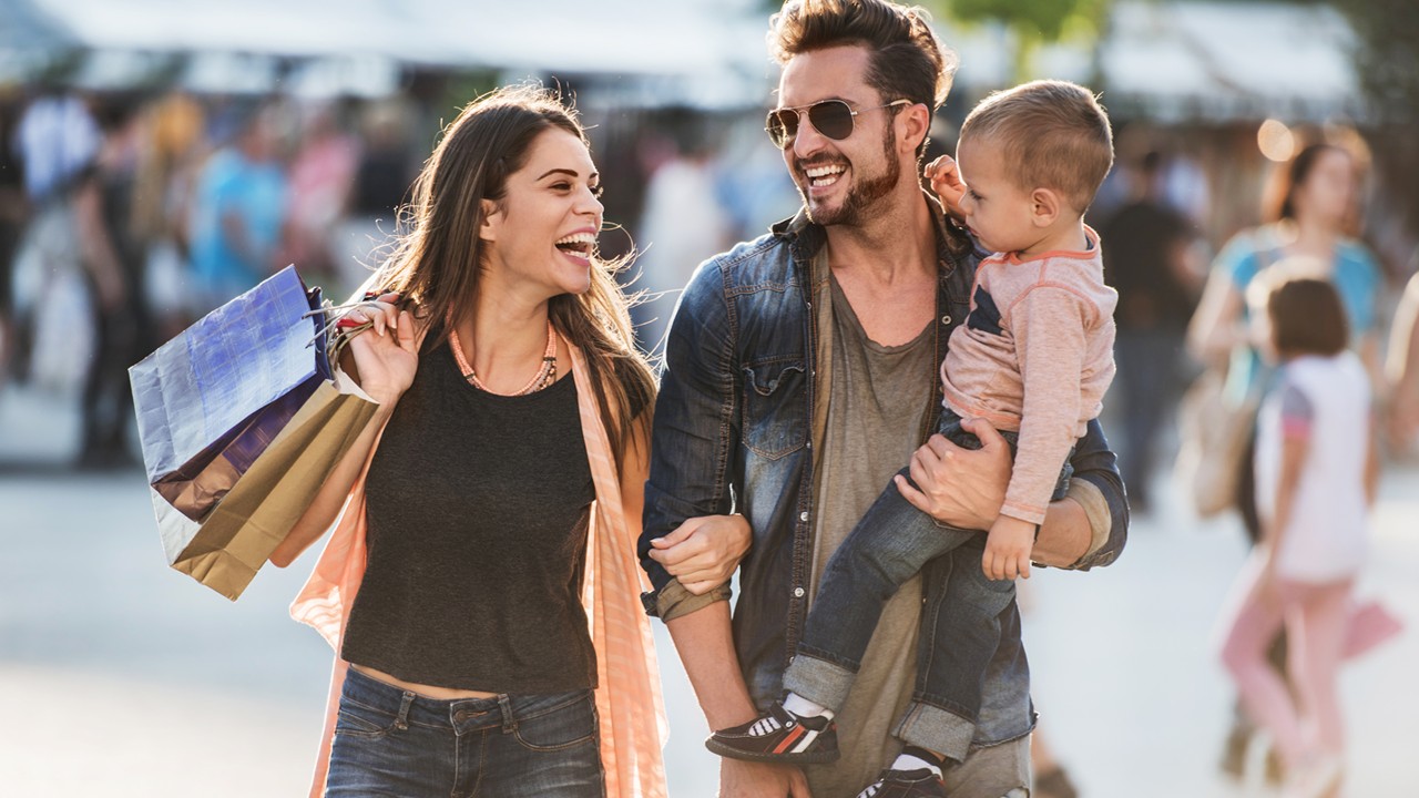a woman holding shopping bags walks happily together with her husband, who's holding a baby;image used for HSBC Credit Card Rewards page