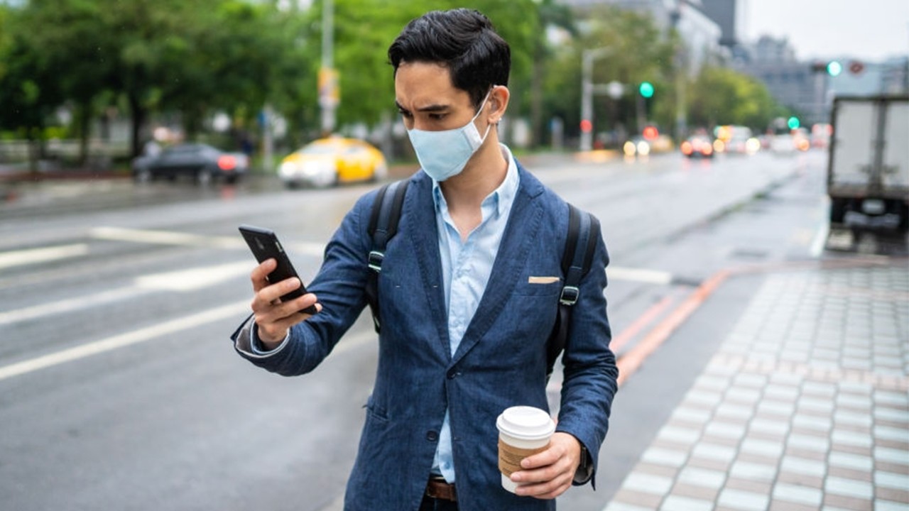 A man wearing a mask looking at the phone