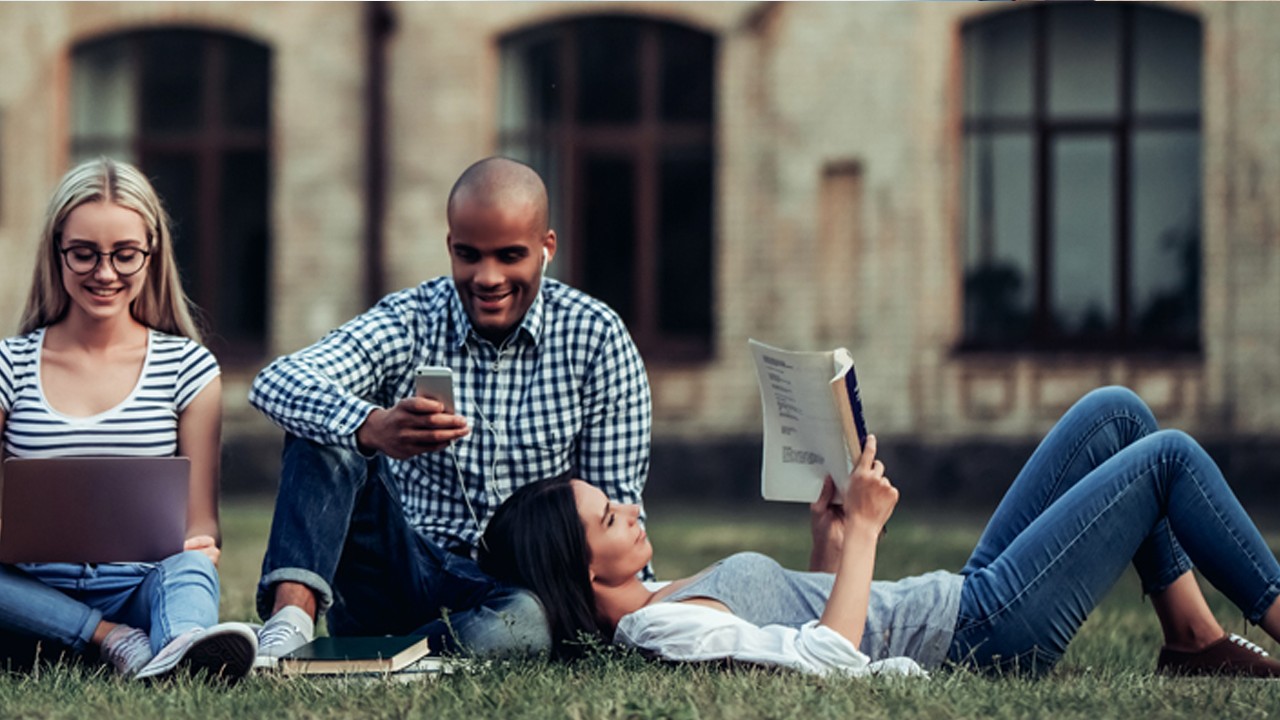 Three students are reading and talking happily on university's grassland; image used for HSBC Premier Next Generation Landing Page