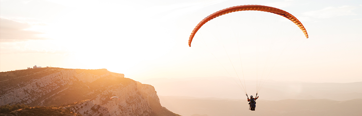 paraglider soaring high above mountains; image used for HSBC LK Premier offers experiences page